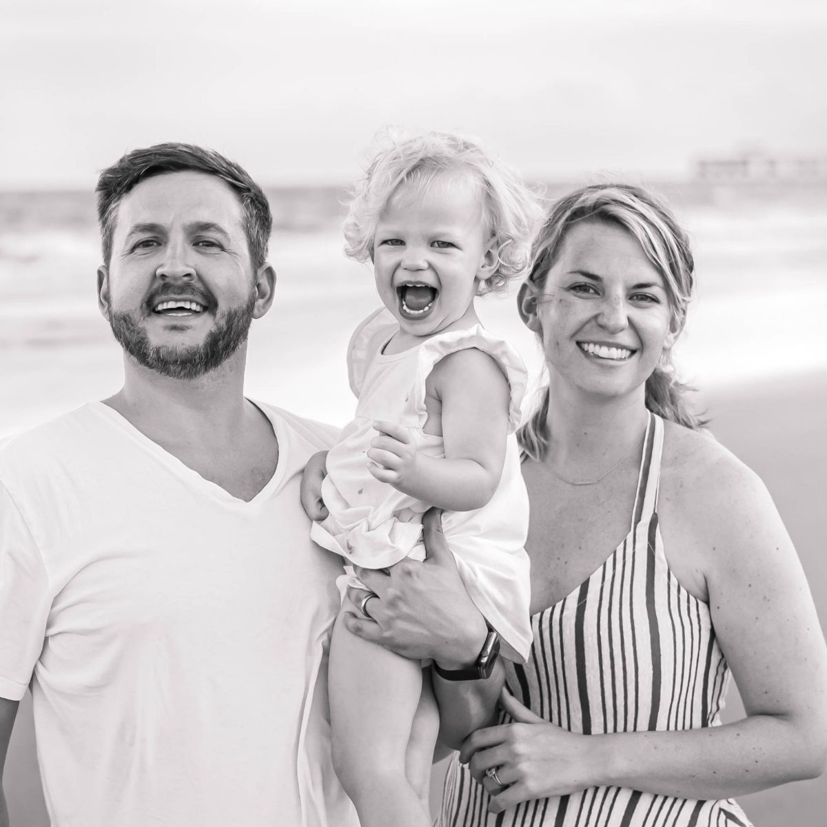 Genni smiles on the beach with her firstborn and husband